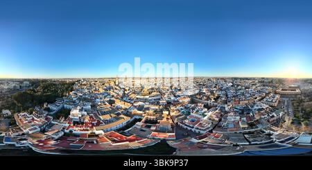 Vista aerea panoramica di un vasto paesaggio urbano sotto un cielo blu limpido, che mostra un mix di architettura tradizionale e moderna, con un orizzonte lontano Foto Stock