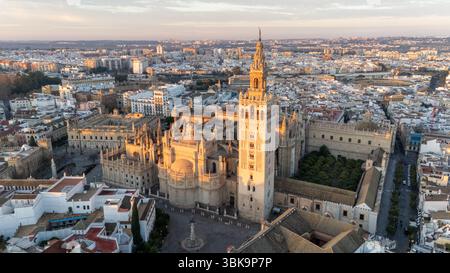 Vista aerea di una cattedrale storica in un paesaggio urbano al tramonto, con una luce calda che illumina l'architettura e gli edifici circostanti. Foto Stock