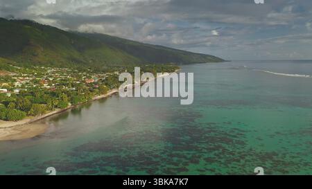 Le incredibili riprese con i droni catturano l'idilliaca bellezza di huahine, la Polinesia francese, con acque turchesi cristalline che si infrangono su una costa lussureggiante tra le vivaci montagne Foto Stock