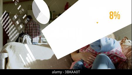 Donna che indossa jeans che tiene a casa il bambino sul divano beige con coperta a pois e sovrapposizione dati. Famiglia, analisi dei dati, digitale, domestico, comfort, bond Foto Stock