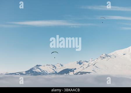 Parapendio che si innalzano sullo sfondo dei picchi avvolti dalle nuvole Foto Stock