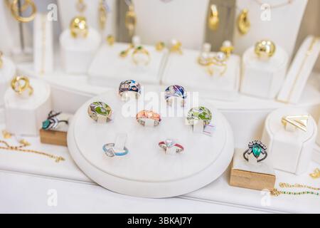 Anelli di design colorati in un'elegante vetrina. Espressione della moda, gioielli moderni e accessori artistici. Foto Stock