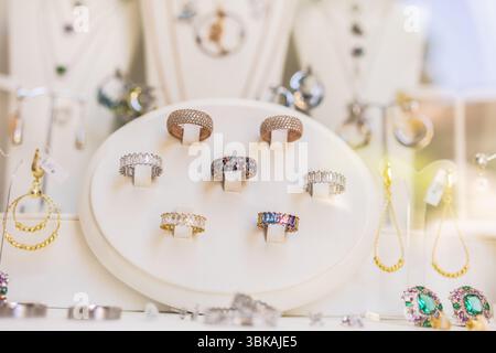 Anelli di design colorati in un'elegante vetrina. Espressione della moda, gioielli moderni e accessori artistici. Foto Stock
