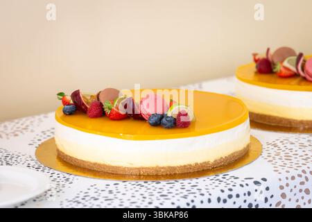 Dessert alla cheesecake decorato con frutta fresca. Uno shot ravvicinato di una cheesecake artigianale, decorata con frutta fresca vibrante e delicati macron. Foto Stock