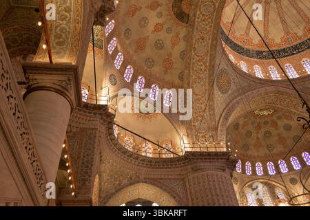 I visitatori ammirano lo splendido design degli interni e le decorazioni ornamentali di una moschea storica di Istanbul, che mostra luminose vetrate colorate. Foto Stock