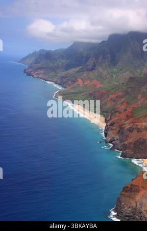 Vista aerea della Napali Coast a Kauai, Hawaii, con scogliere spettacolari, vegetazione tropicale e costa turchese sotto un cielo nebbioso. Foto Stock