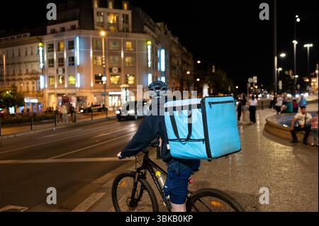 Praga, Repubblica Ceca, 4 agosto 2023. Foto notturna di un operaio in bicicletta di Wolt, una compagnia di consegna di cibo. La borsa blu con la compagnia bianca Foto Stock