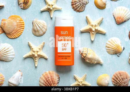 Vista dall'alto della bottiglia di crema solare con oltre 50 scritte e stelle marine su sfondo blu. Concetto di protezione solare Foto Stock