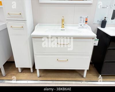 Alicante, Spagna - 18 giugno 2025: Moderno lavandino bianco del bagno con rubinetto e maniglie dorati, dotato di due ampi cassetti esposti in una Foto Stock