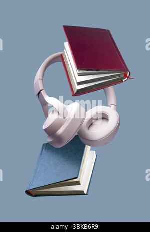 Le cuffie wireless bianche e i libri con copertina rigida volano su uno sfondo blu Foto Stock