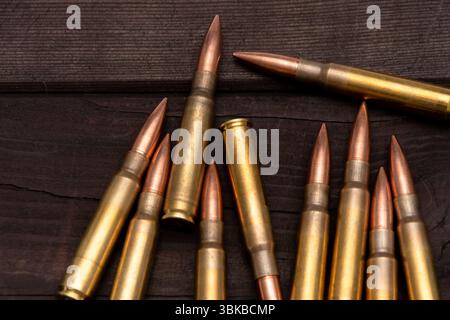 Primo piano di vari calibri di munizioni adagiati su una tavola di legno ruvida. Adatto per argomenti relativi alla caccia, al tiro o agli affari militari Foto Stock