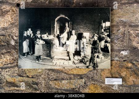 Una vecchia cartolina del Museo Four des Casseaux di Limoges mostra una fotografia di Paul Colmar: Operai che confezionano il forno per la seconda cottura, che avviene a una temperatura compresa tra i 1100 e i 1480 gradi Celsius, a seconda del tipo di porcellana. Caricare e scaricare il grande forno era un lavoro da uomini. Rue Donzelot, Limoges, Nouvelle-Aquitaine, Francia Foto Stock