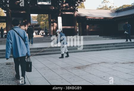 Un operaio spazza con attenzione l'approccio al santuario Meiji Jingu Foto Stock