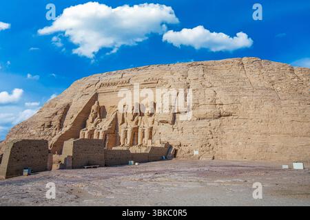 Vista delle colossali statue seduto scolpite sulla scogliera presso gli storici templi di roccia di Assuan sotto il cielo limpido. Abu Simbel, Egitto. Foto Stock