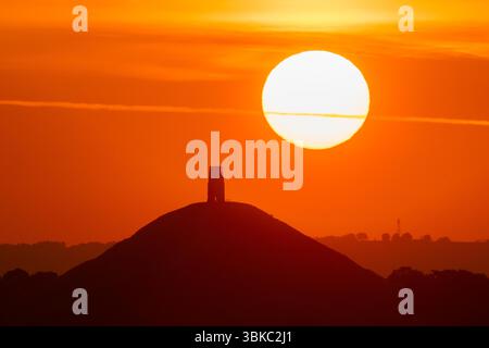 Glastonbury, Somerset, Regno Unito. 20 giugno 2025. Meteo nel Regno Unito. Una spettacolare alba mentre il sole sorge da dietro la St Michael's Tower a Glastonbury Tor nel Somerset in una calda mattina estiva durante l'ondata di caldo. Crediti fotografici: Graham Hunt/Alamy Live News Foto Stock