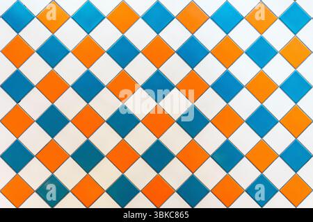 Un vivace sfondo quadrato in ceramica caratterizzato da un mix di piastrelle gialle, blu e bianche. Ideale per illustrare i retroschizzi della cucina, le pareti del bagno o i concetti di design degli interni della casa. Il motivo simmetrico e le linee pulite lo rendono perfetto per l'uso in mood board, grafica di ristrutturazione o branding per un arredamento moderno. Foto Stock