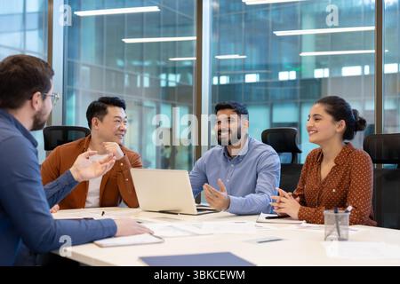 Un gruppo eterogeneo di colleghi collabora in una moderna sala riunioni di ufficio, discutendo idee e strategie. Foto Stock
