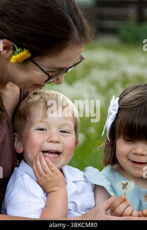 Mamma e bambini condividono i sorrisi dopo aver soffiato il puffball Foto Stock