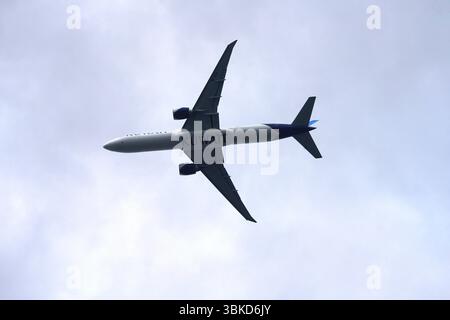Aereo commerciale che vola attraverso il cielo nuvoloso catturato da Ground View. Volo in Kuwait. Greenwich, Londra, Inghilterra Foto Stock