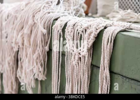 le mani delle donne tessono pannelli in macrame. fili di cotone, filati per la fabbricazione di prodotti fatti a mano per interni. Foto Stock