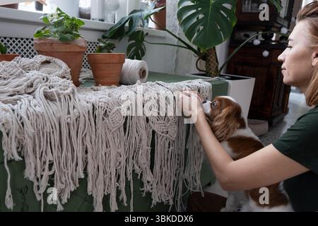le mani delle donne tessono pannelli in macrame. fili di cotone, filati per la fabbricazione di prodotti fatti a mano per interni. Foto Stock