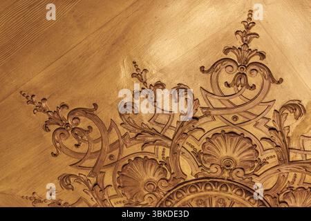 Primo piano di un soffitto decorato in legno caratterizzato da intricati motivi intagliati e motivi tradizionali, trasudando lusso e fascino vintage Foto Stock