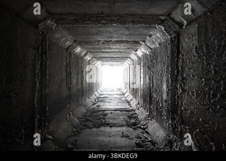 Svuotare il tunnel quadrato di cemento con la luce alla fine Tombini scatolati essiccati. Foto Stock