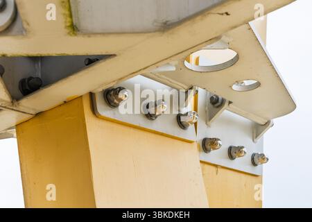 Piastre di rinforzo imbullonate che fissano la trave in acciaio giallo alla colonna, primo piano di ingegneria strutturale Foto Stock