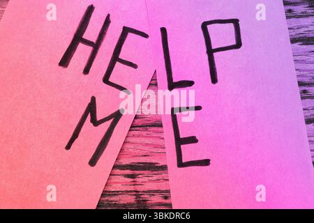 Word HELP ME scritto con penna nera su carta rossa , chiedere aiuto Foto Stock