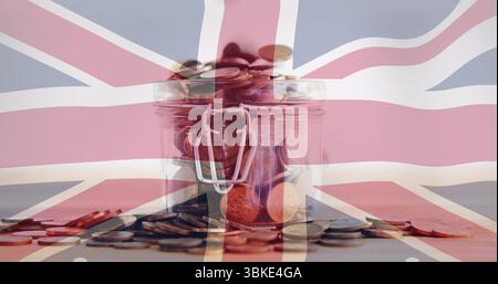 Vaso in vetro che contiene monete assortite su un piano in legno, con copertura bandiera Union Jack Foto Stock