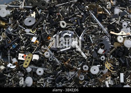 Primo piano di piccole parti meccaniche assortite, ingranaggi, viti e molle di dispositivi smontati, che mostrano dettagli complessi e complessità industriale. Foto Stock