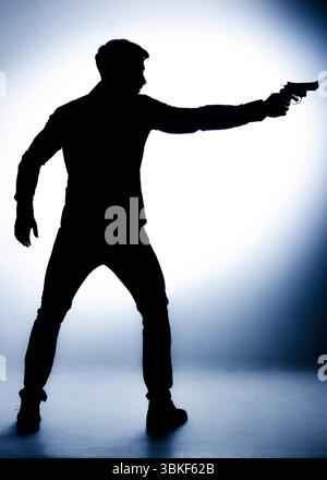 Una figura sagomata, probabilmente un uomo, sta tenendo una pistola e la punta in avanti. L'immagine suggerisce una situazione tesa o pericolosa. Foto Stock
