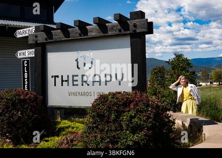 Una donna guarda il cartello del vigneto della terapia a Naramata, nell'Okanagan, British Columbia, Canada Foto Stock