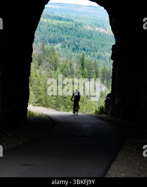 Un uomo di 73 anni fa un giro in bicicletta attraverso il Little Tunnel sul percorso ferroviario Kettle Valley vicino a Naramata, nell'Okanagan, Columbia Britannica, Canada Foto Stock