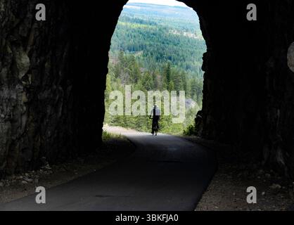Un uomo di 73 anni fa un giro in bicicletta attraverso il Little Tunnel sul percorso ferroviario Kettle Valley vicino a Naramata, nell'Okanagan, Columbia Britannica, Canada Foto Stock