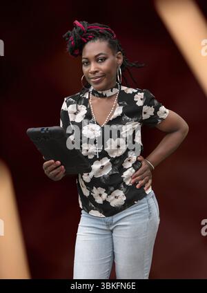 Donna alla moda con acconciatura protettiva che utilizza il telefono cellulare, perfetta per la tecnologia e i concetti di stile di vita Foto Stock