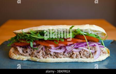 Panino gourmet con tonno e condimenti freschi sul pane artigianale Foto Stock