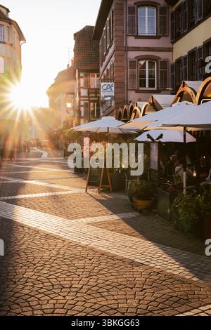 Ribeauvillé, Alsazia, Francia: Ospiti sulla terrazza della Brasserie la Post nel vicolo medievale con case a graticcio retroilluminate dal tramonto Foto Stock