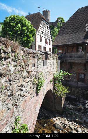 Sul ponte fortificato sul fiume Weiss di fronte alle case in legno nel centro storico di Kaysersberg, Alsazia, Francia Foto Stock