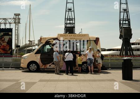 Famiglia che acquista da un furgone gelato e gru, centro Excel, Royal Docks, Londra Foto Stock