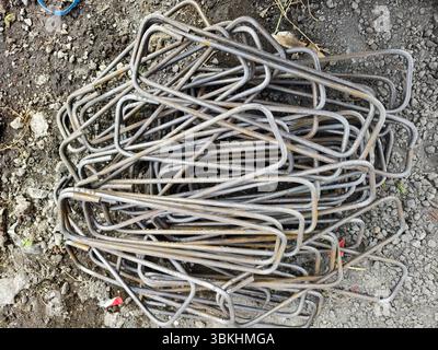 Una pila di barre o staffe in acciaio piegate utilizzate per rinforzare colonne o travi in calcestruzzo Foto Stock