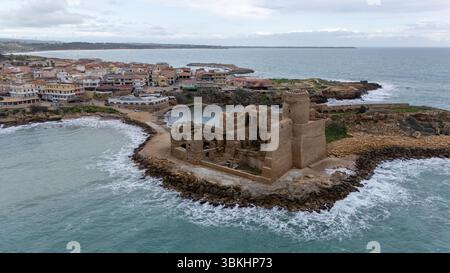 Veduta aerea di un'antica fortezza costiera del Castello di le Castella circondata dal mare, con onde che si infrangono contro la costa rocciosa. Nelle vicinanze, un SM Foto Stock