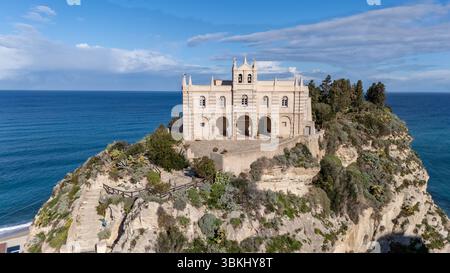 Una chiesa storica arroccata sul Santuario di Santa Maria dell'Isola di Tropeaon, una scogliera che si affaccia sull'oceano, circondata da una vegetazione lussureggiante e da un Foto Stock