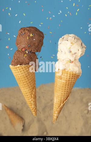 Due coni di gelato, uno con gelato al cioccolato e uno con gelato, su sfondo blu con cospargimenti Foto Stock