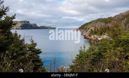 Una vista pittoresca si apre da South Side Road, che si affaccia su Brigus Bay, dove il faro di Brigus si erge come una lontana sentinella. Foto Stock