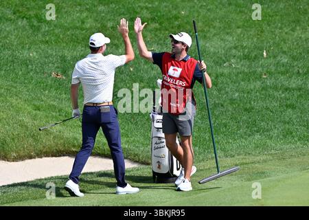 Corregge le date in una versione precedente **.20 giugno 2025: Austin Eckroat di Edmond, OK, celebra con il suo caddy dopo aver fatto il suo colpo da un bunker nella coppa sulla quindicesima buca durante il secondo round del torneo di golf PGA Travelers Championship tenutosi a TPC River Highlands a Cromwell CT. Eric Canha/Cal Sport Media Foto Stock