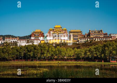 Lo splendido Monastero di Ganden Sumtseling si trova su una collina riflessa in un lago calmo e offre una vista classica di Shangri la. Foto Stock