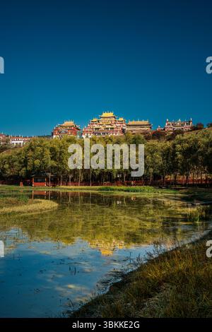 Lo splendido Monastero di Ganden Sumtseling si trova su una collina riflessa in un lago calmo e offre una vista classica di Shangri la. Foto Stock