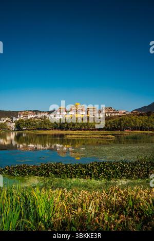 Lo splendido Monastero di Ganden Sumtseling si trova su una collina riflessa in un lago calmo e offre una vista classica di Shangri la. Foto Stock