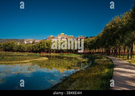 Lo splendido Monastero di Ganden Sumtseling si trova su una collina riflessa in un lago calmo e offre una vista classica di Shangri la. Foto Stock